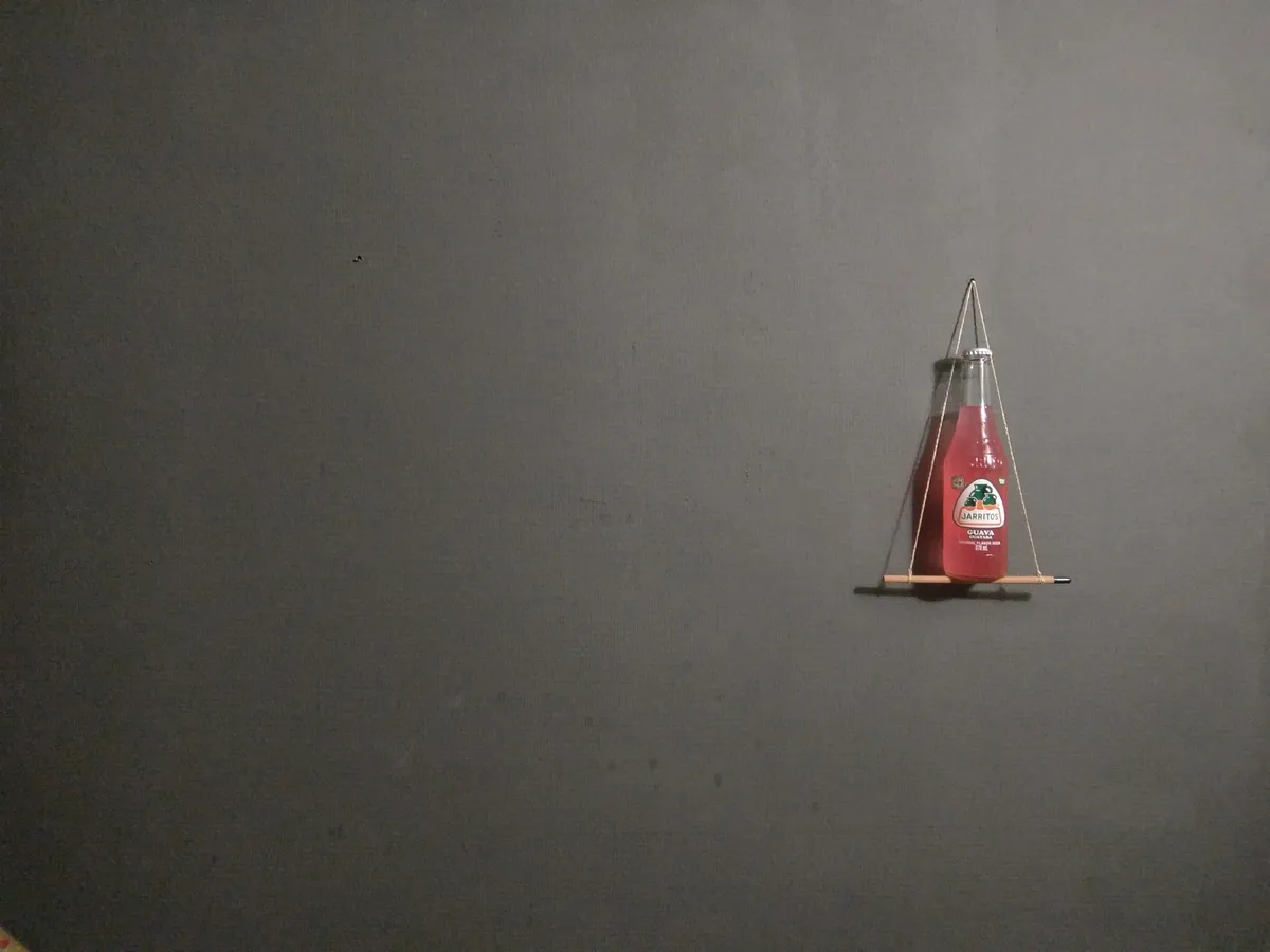 Flasche Jarritos Guava auf einem Mini-Bleistiftgestell vor grauer Wand