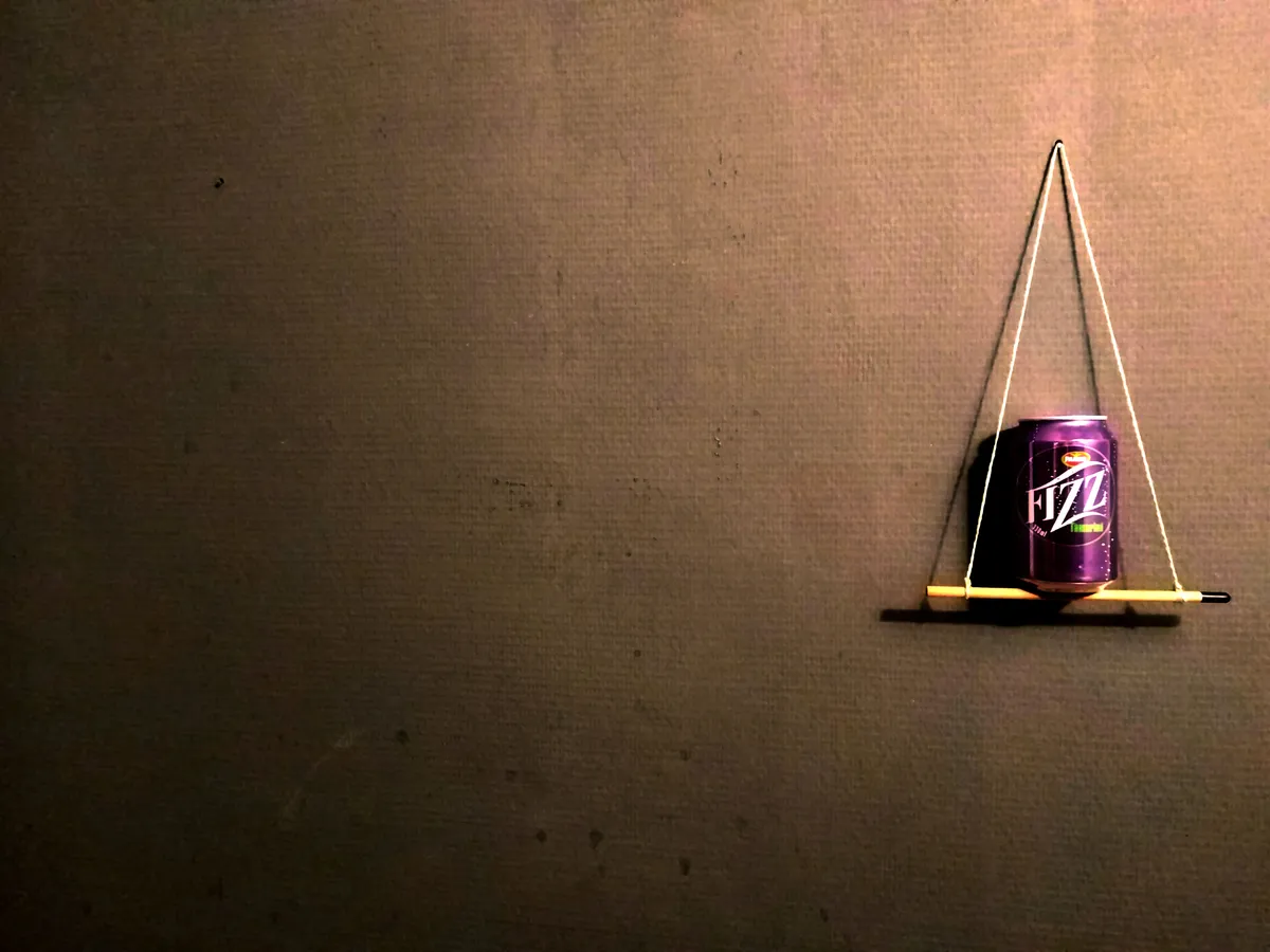 Dose Pampa Fizz Tamarind auf einem Mini-Bleistiftgestell vor dunkler Wand