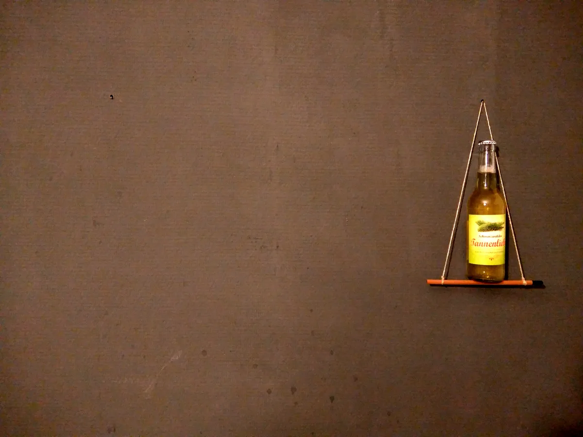 Flasche Schwarzwälder Tannenliebe auf einem Mini-Bleistiftgestell vor dunkler Wand